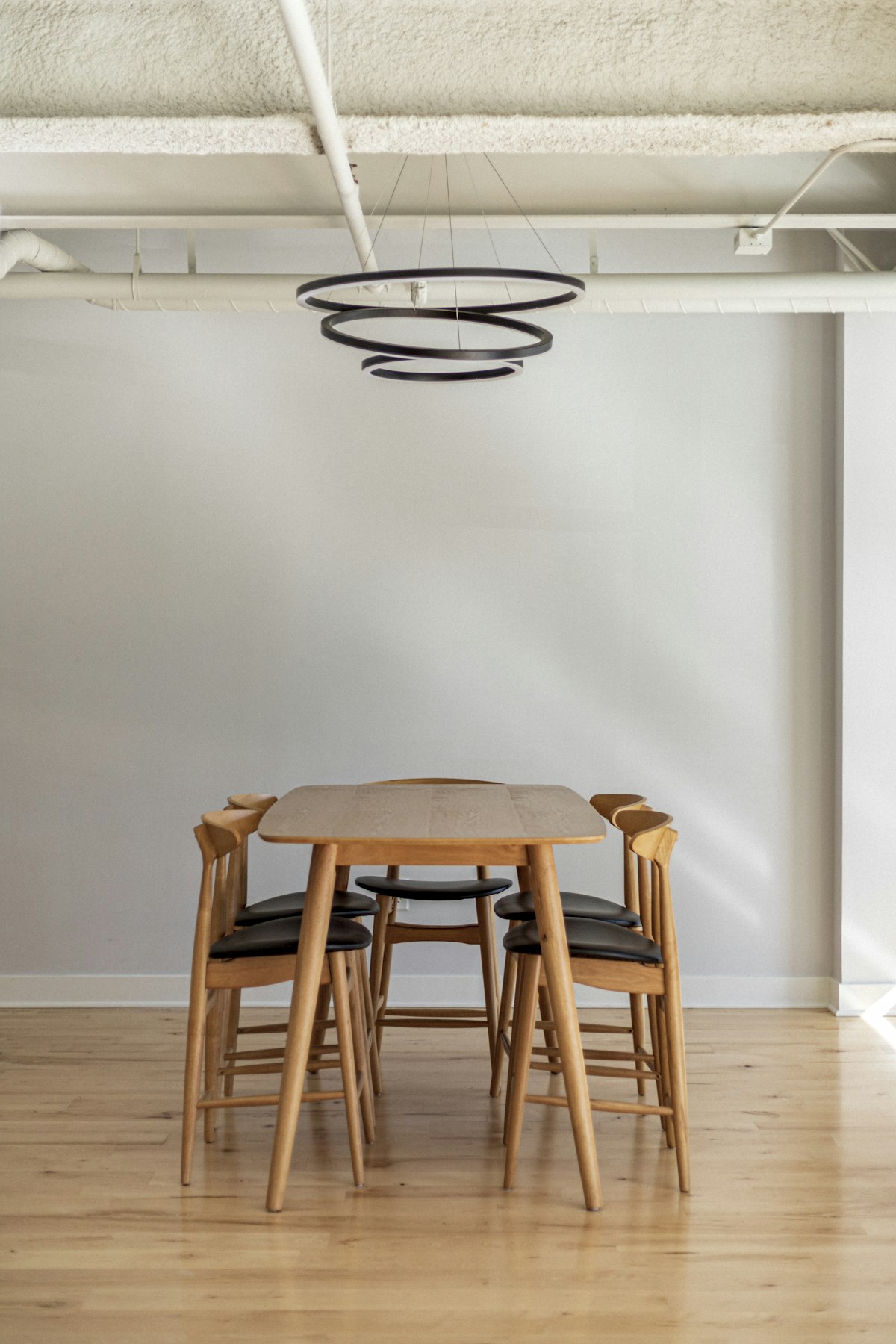 Solid oak dining table with matching chairs beneath a ring pendant