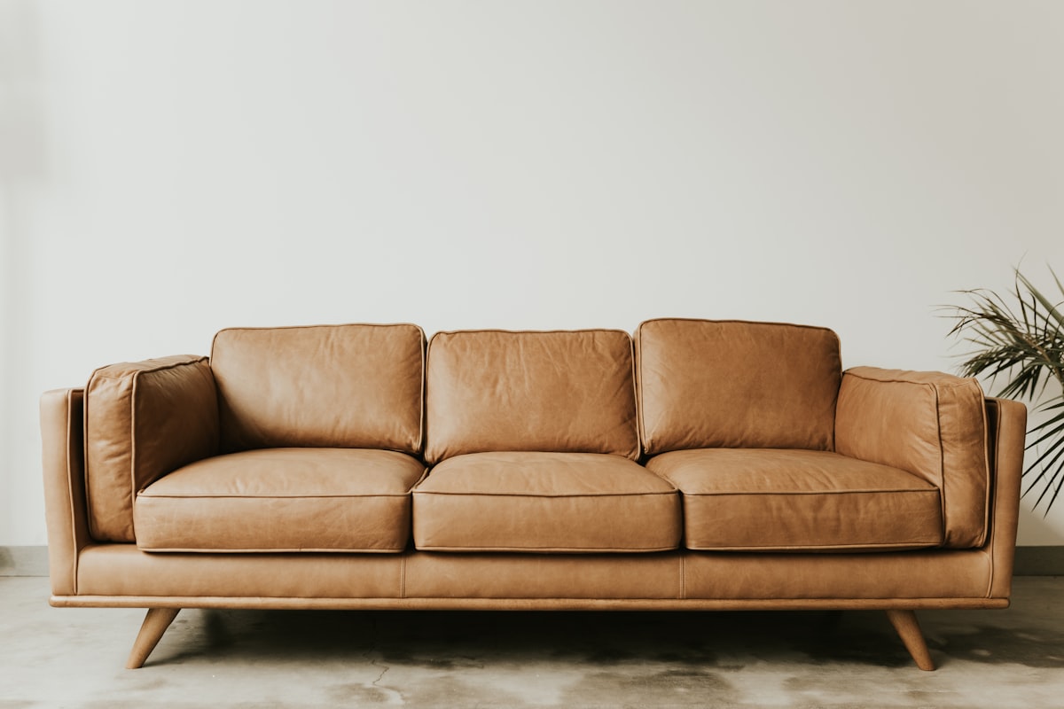 Tan leather three-seat sofa on a slim hardwood frame