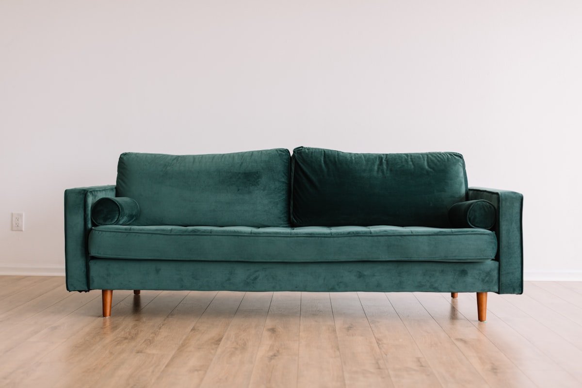 Deep green velvet two-seat sofa on turned wooden legs