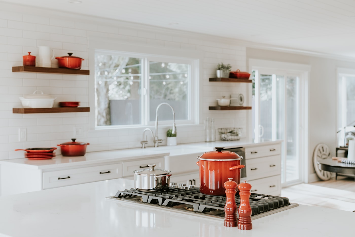 Bright kitchen with walnut floating shelves above a painted base run